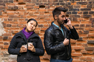 young man talking on the phone, girl misses with two paper cups of coffee