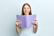 © the faces - pleasant cute clever woman with freckles holding a book, reading it, student preparing for exams. close up portrait, isolated white background, studio shot