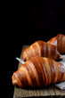© kcuxen - Golden croissants of yeast dough on the edge of the wooden table against black background