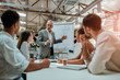 © Kostiantyn - Confident mature businessman pointing at white blackboard and explaining something to his young colleagues during meeting in the office