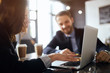 © the faces - young woman's hands on laptop. serious attractive brown-haired woman concentretaed on working with laptop, while her colleague watching her, blurred background