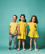 © FAB.1 - Studio portrait of children on a light background: full body shot of three children in bright clothes, two girls and one boy. Triplets, brother and sisters.