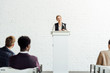 © LIGHTFIELD STUDIOS - attractive businesswoman standing and smiling during conference in conference hall