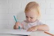 © Delete - Cute baby girl coloring picture with pencil on white background