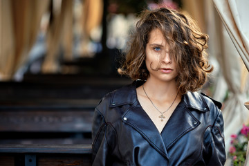 Portrait of beautiful lady with wild curly hair standing near terrace