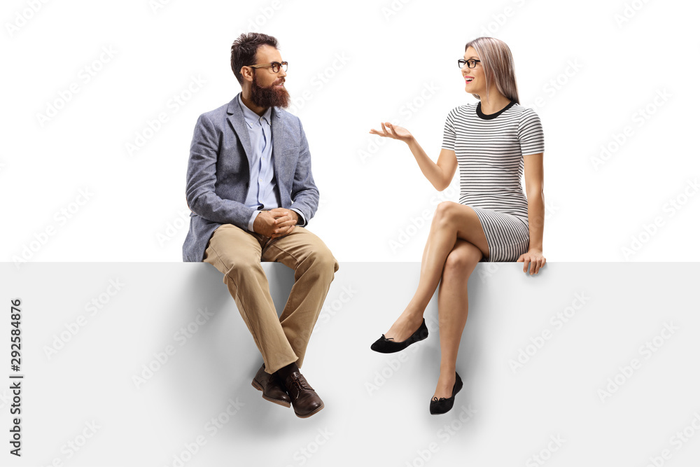 Young woman having a conversation with a bearded man while sitting on a panel - obrazy, fototapety, plakaty 