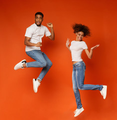 Carefree african american man and woman jumping in air