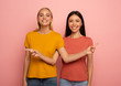 © alphaspirit - Two girls indicates something. Joyful expression face. Pink background with blank space for your text