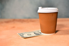 Cash Tip Concept With Cup Of Coffee And One American Dollar On A Table