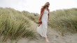 young blonde woman looking thoughtful, head down, wearing a long white dress, brown jacket, carrying sandals, descending barefoot sandy sea grass covered hill