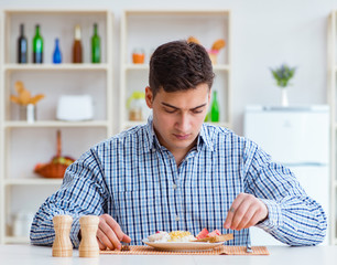 Wall Mural - Young husband eating tasteless food at home for lunch