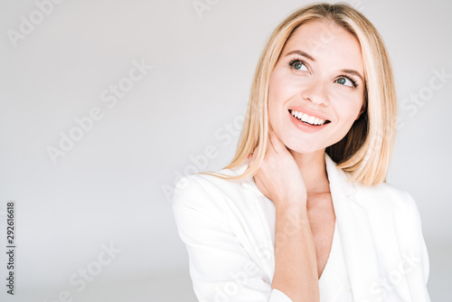 Cuadros en Lienzo smiling beautiful young blonde woman in total white outfit looking away isolated