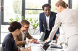 © LIGHTFIELD STUDIOS - multiethnic businesspeople in formal wear at table during conference in office
