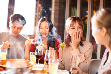 happy young friends enjoy dinner in hot pot restaurant