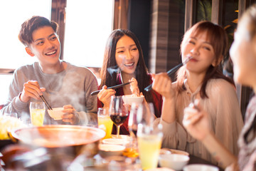 Wall Mural - happy young friends enjoy dinner in hot pot restaurant