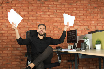 Young business man in casual wear is expressing joy while holding documents in his hands