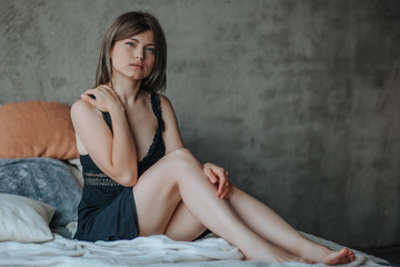 Wall Mural - Cute girl sitting on bed in morning in black lingerie