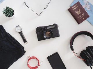 Wall Mural - top view travel concept with retro camera films, map, passport, smartphone and Outfit of traveler on white table background, Tourist essentials, vintage tone effect