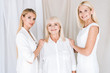 © LIGHTFIELD STUDIOS - smiling elegant three-generation blonde women in total white outfits