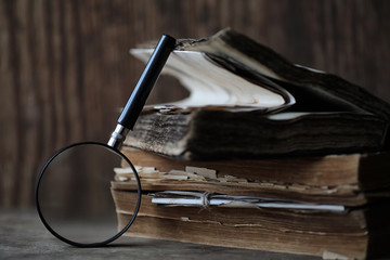 Canvas Print - Old books on a wooden table and magnifier