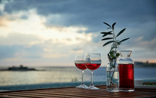 Two Glasses Of Rose Wine With  Olives Against Blue Water On A Pier..
