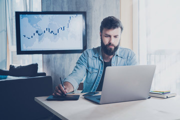 Digital specialist sitting at office desk and working on laptop and tablet. Developer using wireless solutions in work. Young programmer watching webinar, taking distant education courses on internet