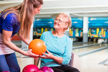 Mother Giving Bowling Ball To Her Daughter