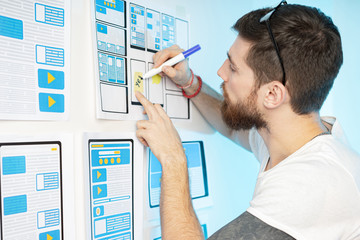 The man works as a designer of mobile applications. The designer develops the most convenient user interface of the program. Use of special templates for convenience. UI. UX
