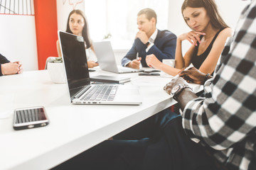 A team of young office workers, businessmen with laptop working at the table, communicating together in an office. Corporate businessteam and manager in a meeting. coworking.