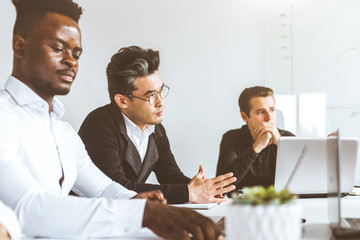 A team of young businessmen working and communicating together in an office. Corporate businessteam and manager in a meeting.