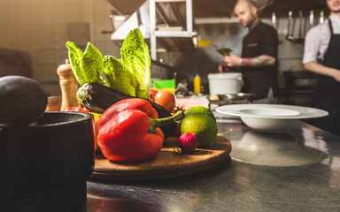 Wall Mural - Professional chef cooking in the kitchen restaurant at the hotel, preparing dinner. A cook in an apron makes a salad of vegetables and pizza.