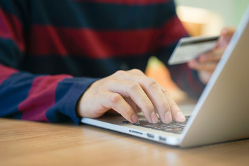 close up young caucasian man typing passcode on laptop and holding credit card for payment after finished to choose item on marketplace website on cyber monday and black friday season at room