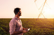 © Zoran Zeremski - Young farmer holding tablet in his hands and adjusts irrigation system on soybean field at sunset.