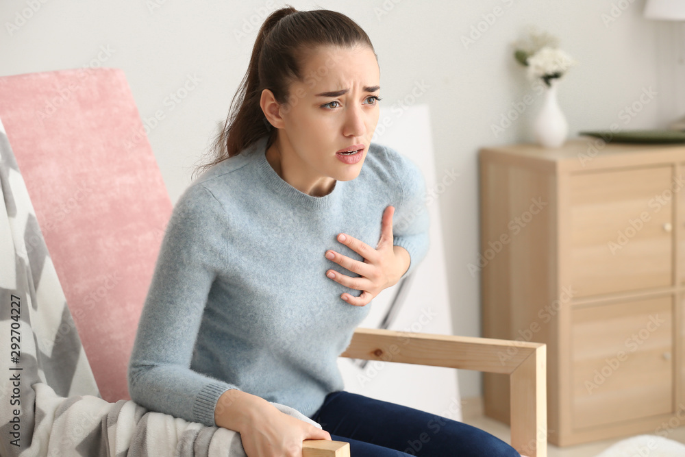 Young woman suffering from heart attack at home