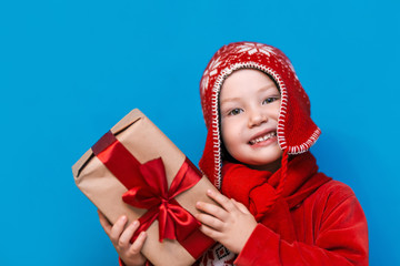 Wall Mural - little boy in Santa's hat with cozy gift box and red tape want to know what inside the box, put to his ear