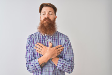 Poster - Young redhead irish man wearing casual shirt standing over isolated white background smiling with hands on chest with closed eyes and grateful gesture on face. Health concept.