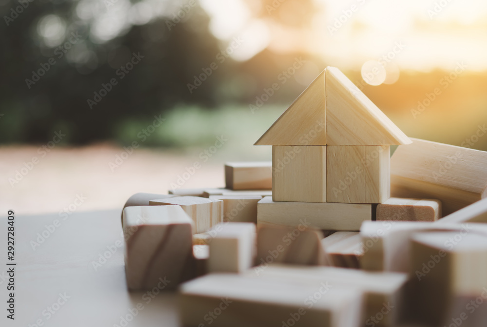 house from natural color wooden block on the stack of wooden blocks with orange light effect - obrazy, fototapety, plakaty 