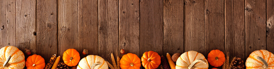 Wall Mural - Autumn bottom border banner of pumpkins and fall decor on a rustic wood background with copy space