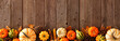 Autumn bottom border banner of pumpkins, gourds and fall decor on a rustic wood background with copy space