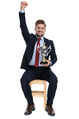 Wall Mural - proud businessman holding trophy and holding hand in the air