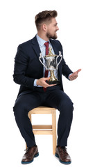 Wall Mural - proud young businessman holding trophy in studio