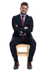 Sticker - happy young businessman sitting with arms folded