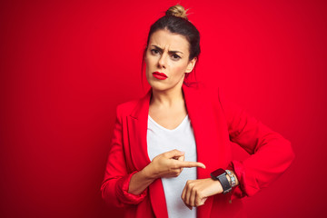 Canvas Print - Young beautiful business woman standing over red isolated background In hurry pointing to watch time, impatience, upset and angry for deadline delay