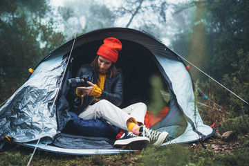 Wall Mural - photographer tourist traveler take photo on camera in camp tent in foggy rain forest, hiker woman shooting mist nature trip, green tourism, rest vacation camping holiday