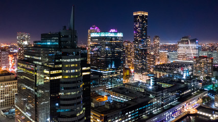 Fototapete - Aerial view of Jersey City skyscrapers by night from a drone flying above Hudson river.