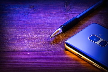 pen and blue mobile phone on a wooden background