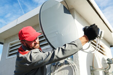 Service Worker Installing And Fitting Satellite Antenna Dish For Cable TV