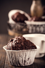 Wall Mural - Chocolate muffins with banana in white paper cups on dark wooden background. Party food concept.