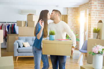 Young couple moving to a new home, hugging in love showing keys of new apartment smiling very happy