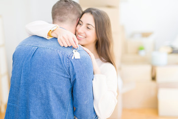 Poster - Beautiful young couple hugging in love and showing keys of new house, smiling happy moving to a new apartment